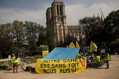 People fix a banner that reads in French: "Notre-Dame is roofless, we too!" during a protest in front of the Notre Dame cathedral in Paris, Monday, April 22, 2019. (AP Photo/Francisco Seco)