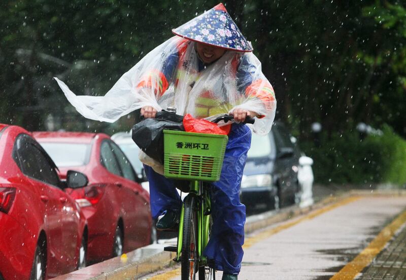 A Chinese sanitation worker rides a bicycle against the strong winds caused by Typhoon Hato on a road along the seacoast in Zhuhai, in China's southern Guangzhou province. AFP.