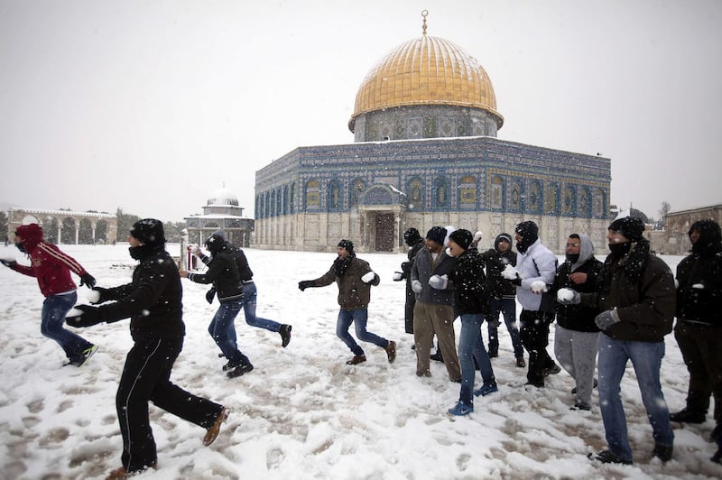 Palestinians play with snow outside the Dome of the Rock at the Al-Aqsa mosque compound in the old city of Jerusalem on January 10, 2013. Jerusalem was transformed into a winter wonderland after heavy overnight snowfall turned the Holy City and much of the region white, bringing hordes of excited children onto the streets. AFP PHOTO/AHMAD GHARABLI

