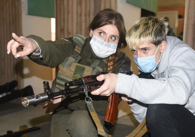 A military instructor teaches a schoolboy to shoot with Kalashnikov rifles, during a training session in Lviv. AFP