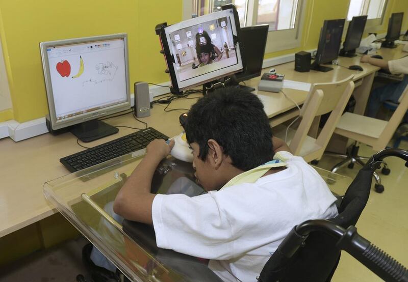 Harshil Shetty works using a specially adapted mouse on a computer at Al Noor Training Centre. Jeffrey E Biteng / The National 