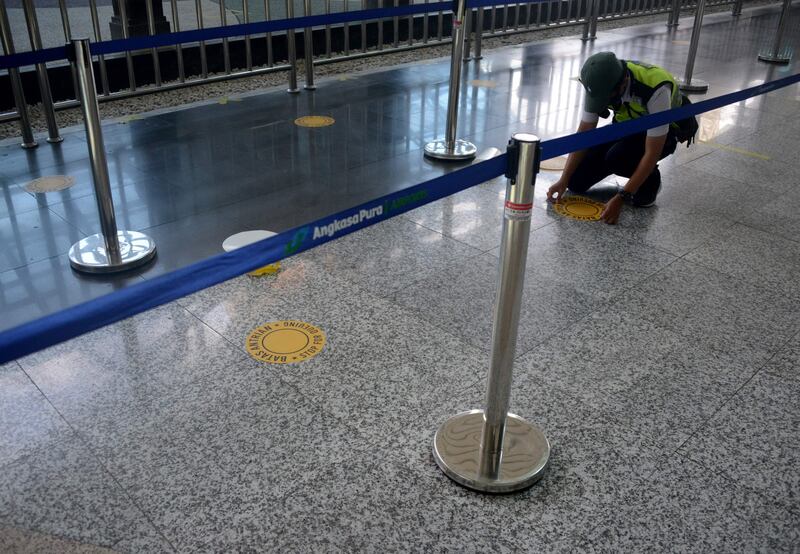 An airport officer places a  social distancing sticker in the international arrivals terminal at Ngurah Rai airport in Tuban on Indonesia's resort island of Bali on October 14. AFP