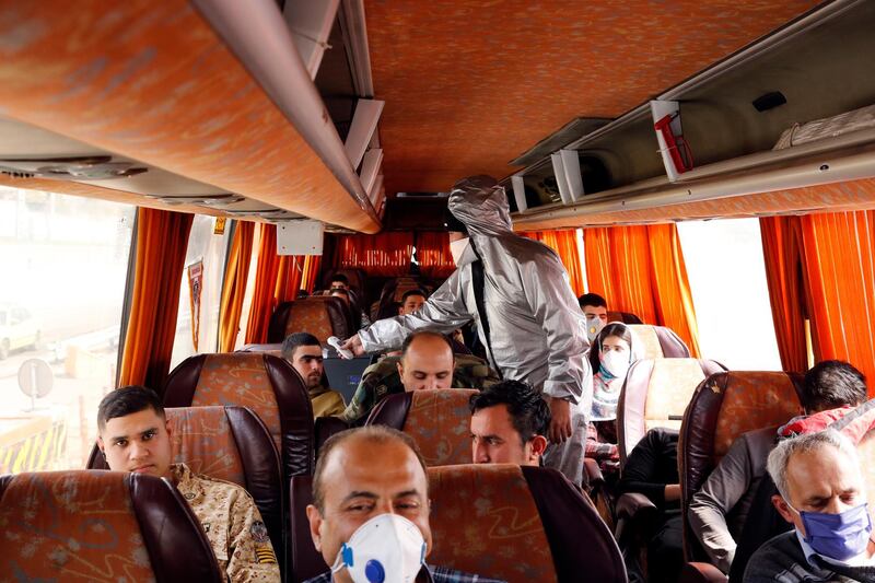 A member of Iranian Red Crescent tests passengers of a bus for possible coronavirus Covid-19 symptoms, as police blocked Tehran to Alborz highway. EPA
