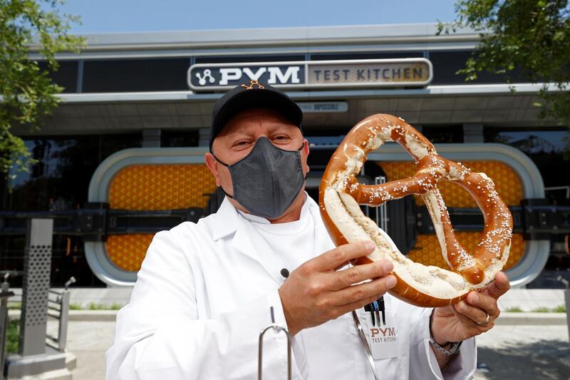 Juan Lugo, executive chef at Disneyland Resort, holds a large pretzel from Pym Test Kitchen ahead of the opening of the Avengers Campus. Reuters