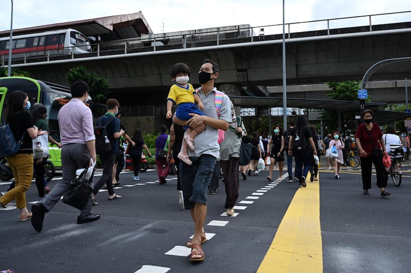 A man with a child crosses a street in Singapore this week. Singapore's Prime Minister Lee Hsien Loong called a general election "like no other" last week as the city-state struggles to recover from the coronavirus outbreak. AFP