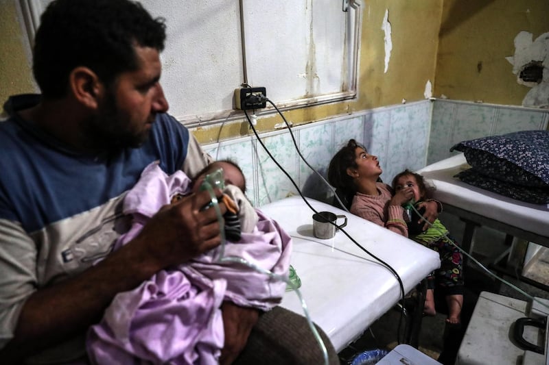 An affected man puts the aerosol mask on his child while his other daughter gives treatment to her other sister after a shelling attack on rebels-held Eastern Ghouta. EPA