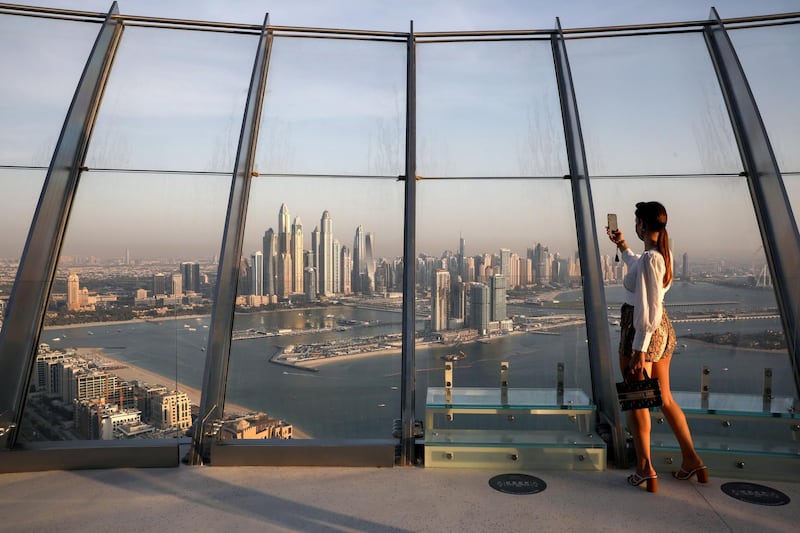 A woman takes a picture with a smartphone of the upscale Marina district from the Palm Tower in Dubai, United Arab Emirates, June 9, 2021. Picture taken June 9, 2021. REUTERS/Christopher Pike