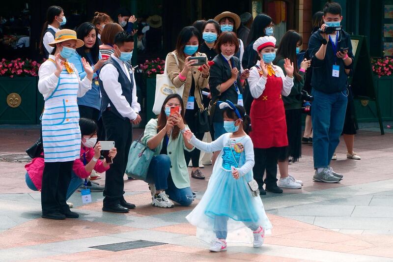 A young visitor, wearing a face mask, waves as she enters Shanghai Disneyland. AP Photo