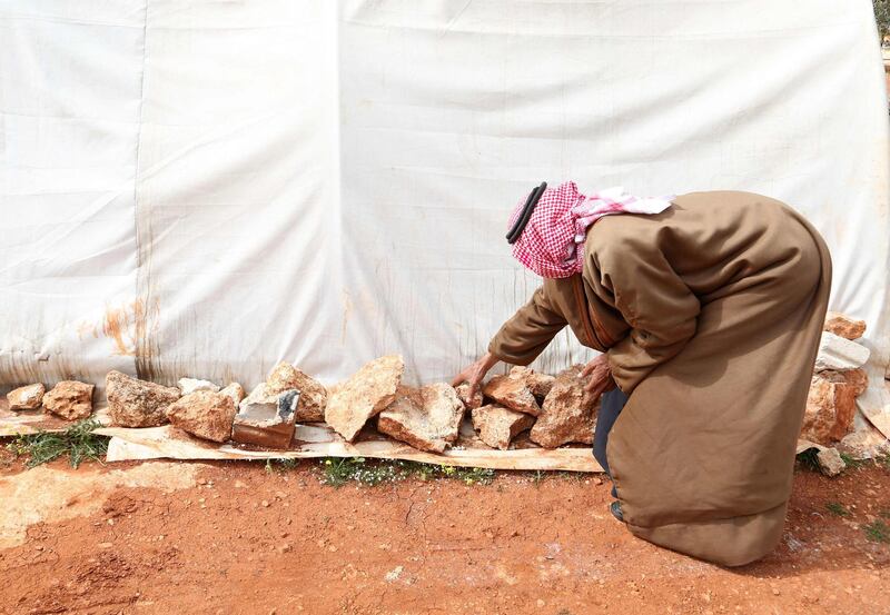 Abderrazaq Khatoun places rocks to protect one of his tents from wind. AFP