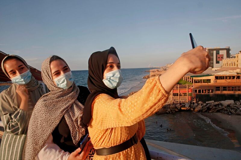 Palestinian women takes a selfie at sunset in Gaza city amid strict restrictions due to the COVID-19 pandemic.  AFP