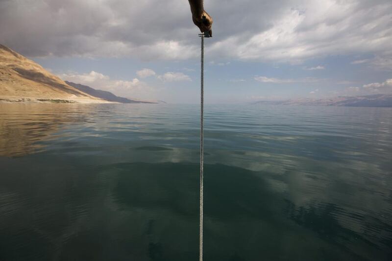 A researcher from the Isareli Geological Institute of Limnological Research measures the Dead Sea depth from a rope covered with salt while sailing on the research  ship ‘Taglit’ (Discovery) during their monthly research of the Dead Sea water level.