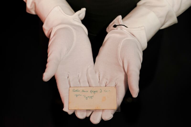 A member of Christie's staff holds a note written by Beatle George Harrison, part of a collection being sold by his former wife Pattie Boyd, at the auction house in London, UK. The note is expected to fetch between £2,000 and £3,000. AP