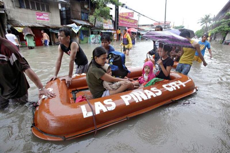 Filipino women and their children ride a rescue boat as they evacuate their flooded homes in Las Pinas, south of Manila, Philippines on Monday, Aug. 19, 2013. Torrential rains brought the Philippine capital to a standstill Monday, submerging some areas in waist-deep floodwaters and making streets impassable to vehicles while thousands of people across coastal and mountainous northern regions fled to emergency shelters. (AP Photo/Aaron Favila)