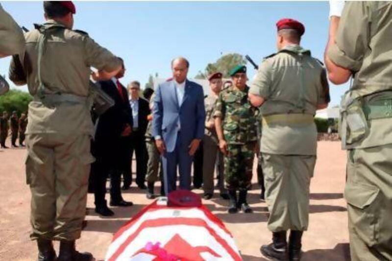 President Moncef Marzouki stands in front of a coffin, draped in the Tunisian flag, of one of eight soldiers who died in an ambush by an armed group in Mount Chaambi, near the Algerian border.