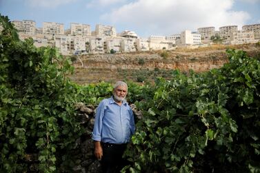 Palestinian man Mohammad Awad, 64, poses for a photo at his farm in the village of Wadi Fukin with the Jewish settlement of Beitar Illit in the background, in the Israeli-occupied West Bank, July 21, 2019. Reuters