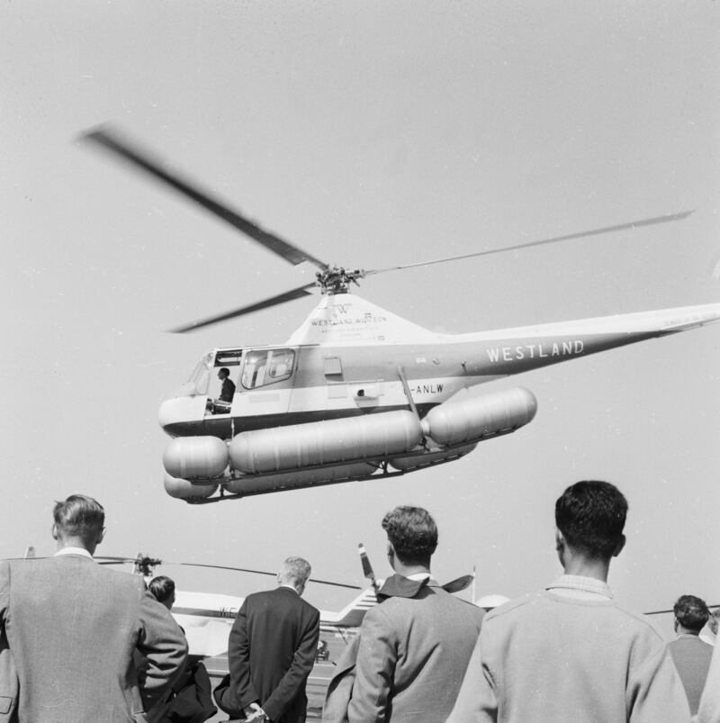 A Westland Widgeon helicopter hovers above the Farnborough Airshow crowd in 1959.