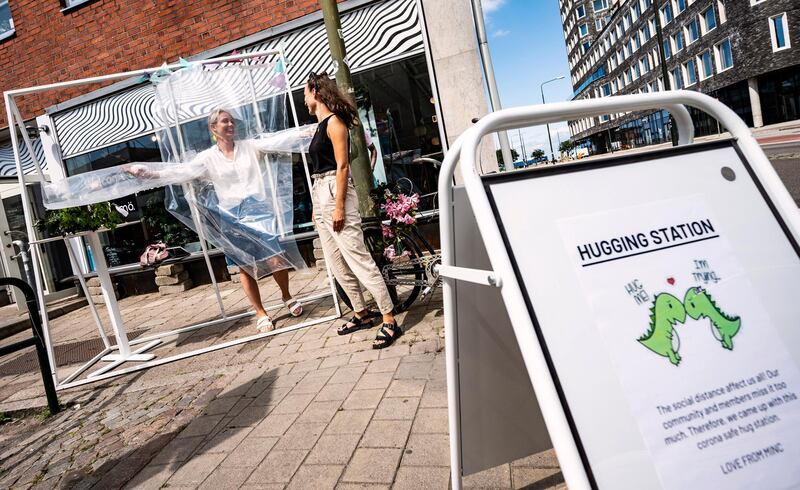 People get ready at a hug station at The Minc company in Malmoe, Sweden. The hug station was created so that those working at Minc would have the opportunity to give each other a hug, protected by a sheet of plastic, before going on vacation AP