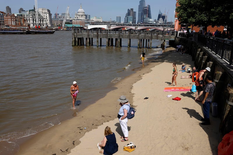 People cool off beside the River Thames. AFP