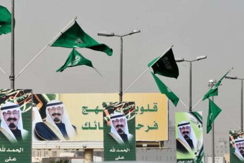 Saudi flags flutter above pictures of King Abdullah bin Abdul Aziz decorating a street in the Saudi capital Riyadh on February 23, 2011 as he flew out of Morocco and headed home after recovering from back surgery. AFP PHOTO/FAYEZ NURELDINE
 *** Local Caption ***  360210-01-08.jpg