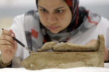 An Egyptian conservator works on an ancient Pharaonic wooden statue of the Egyptian god Osiris, at the wood laboratory of the restoration center of the partially opened complex of the Grand Egyptian Museum in Cairo. Amr Nabil / AP Photo