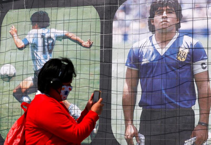 A person takes a video of a billboard in homage to Argentinian legend Maradona on his 60th birthday, near the Buenos Aires' Obelisk. Reuters