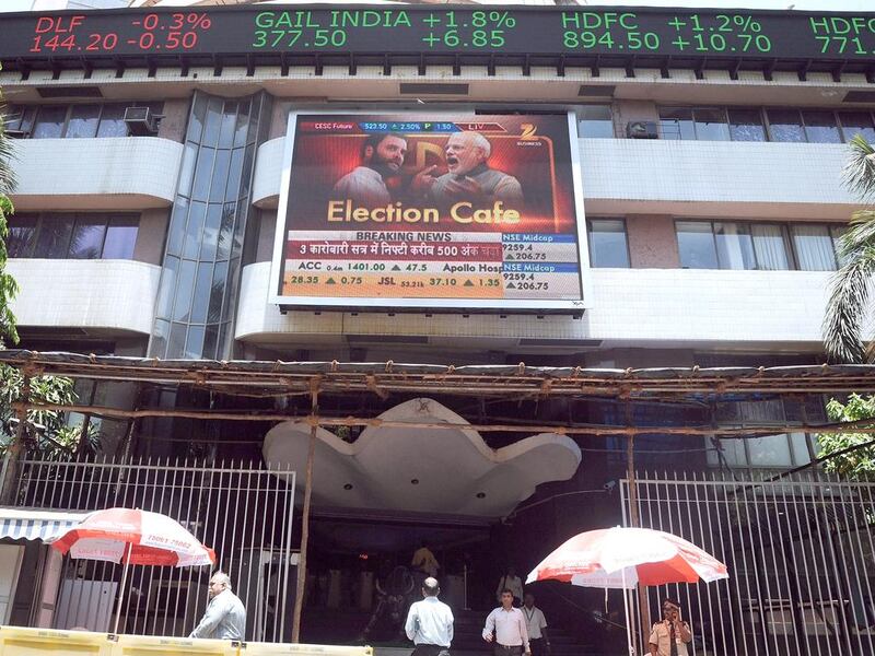 Indian officegoers walk past the Bombay Stock Exchange (BSE) as the digital broadcast shows the 30 share benchmark index SENSEX cross 24,000 points during intra-day trade in Mumbai on May 13, 2014.  India's stock market surged for the third straight day to a record high May 13 as exit polls indicated that Hindu nationalist party leader Narendra Modi was on course to become the country's next prime minister.  INDRANIL MUKHERJEE / AFP

