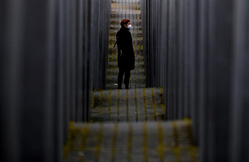 A woman in an anti-coronavirus mask walks between steles of the Memorial to the Murdered Jews of Europe in Berlin, Germany. Germany has extended and strengthened its lockdown measures until April 18.  EPA