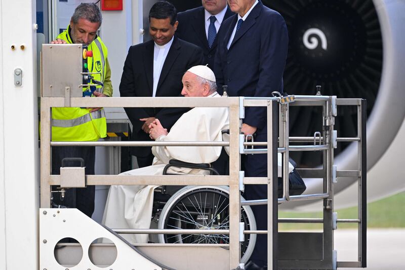 Pope Francis, seated on a wheelchair, is lifted on a platform to board the plane. AFP