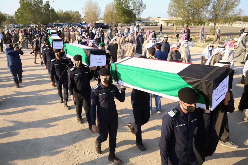 Families carry the coffins of eight Kuwaiti prisoners of war (POWs) whose remains were found in a mass grave in Iraq and identified following a DNA test, during a funeral procession at a cemetary in Kuwait City on January 13, 2021. - Kuwait identified remains belonging to thirteen Kuwaiti POWs or missing persons after DNA tests were conducted by the General Administration of Criminal Evidence, according to local media. The prisoners were arrested during the Iraqi invasion of the Gulf emirate in 1990 when Iraqi tyrant Saddam Hussein sent his military into Kuwait to seize what he dubbed "Iraq's 19th province. (Photo by YASSER AL-ZAYYAT / AFP)