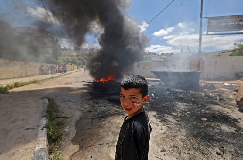 A Palestinian child keeps his distance from burning tyres in the refugee camp of Jenin in the occupied West Bank after an Israeli military raid.