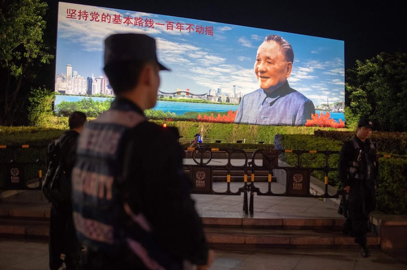 In this picture taken on December 17, 2018, security personnel secure an area in front of a billboard featuring China's late paramount leader Deng Xiaoping on the eve of the 40th anniversary of China's "reform and opening up" policy in Shenzhen. China celebrates on December 18 the 40th anniversary of its transformative "reform and opening up" policy, which turned the world's most populous country into an economic juggernaut that now faces slowing growth and a stern US challenge. / AFP / Nicolas ASFOURI

