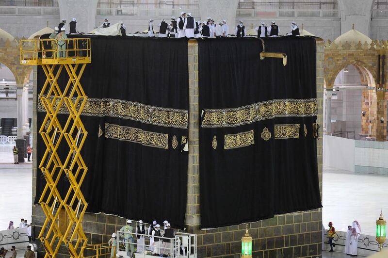 Saudi labourers put the new Kiswa, the protective cover that engulfs the Kaaba, made from black silk and gold thread and embroidered with Koran verses in Saudi Arabia's holy city of Mecca.  AFP