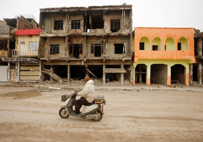 A man drives his motorbike next to damaged buildings in Mosul. Reuters