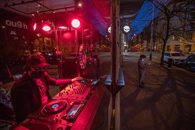 A DJ wearing protective face mask performs behind a window in Prague, Czech Republic.  EPA