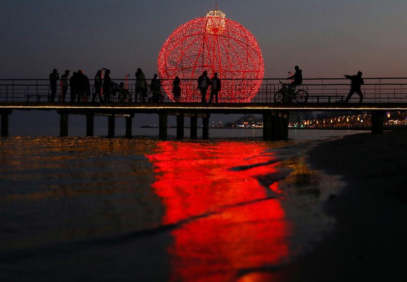 People are seen on a pier in front of a giant illuminated Christmas ball in Larnaca, Cyprus. REUTERS