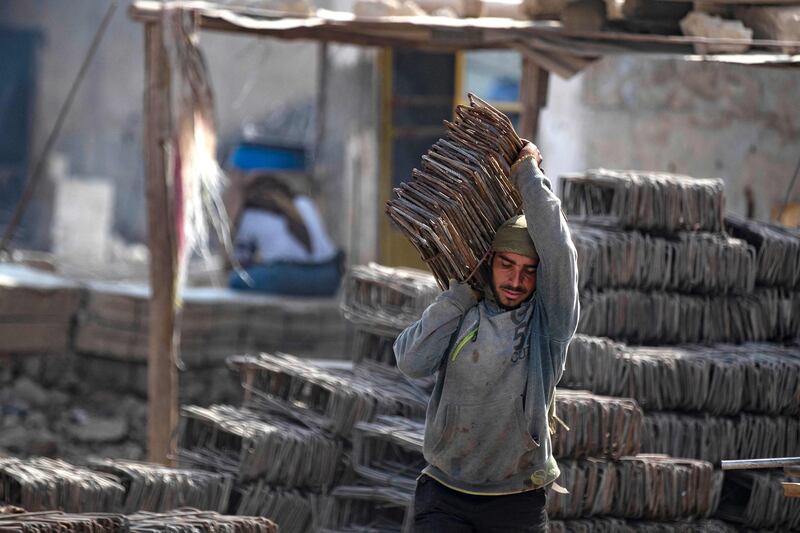 Workers carry steel rods to reuse or melt.