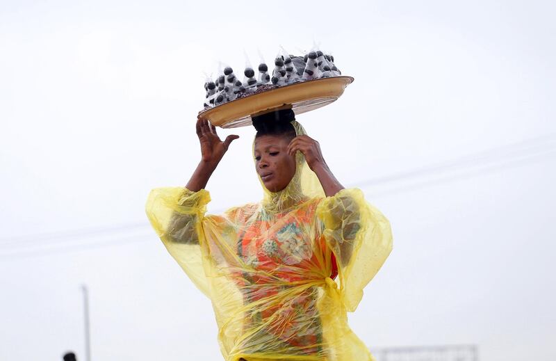 A woman carries walnuts arranged in a tray along a road during rainfall in Lagos, Nigeria. EPA