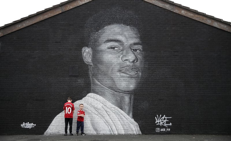 Jacob (left) and Joshua Hallighan in front of a mural of Manchester United striker Marcus Rashford by Street artist Akse on the wall of the Coffee House Cafe on Copson Street, Withington. PA Photo. Picture date: Sunday November 8, 2020. Manchester United forward Marcus Rashford has drawn widespread praise for his role in highlighting the issue of child food poverty, which has been exacerbated by the economic impact of the coronavirus pandemic. See PA story SOCCER Rashford. Photo credit should read: Martin Rickett/PA Wire.