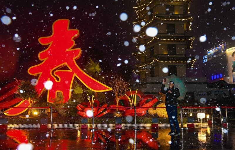 A man takes photos as he stands next to an installation with a Chinese character reading, 'Spring', amid snow ahead of the upcoming Chinese Lunar New Year in Zhengzhou, China. Reuters