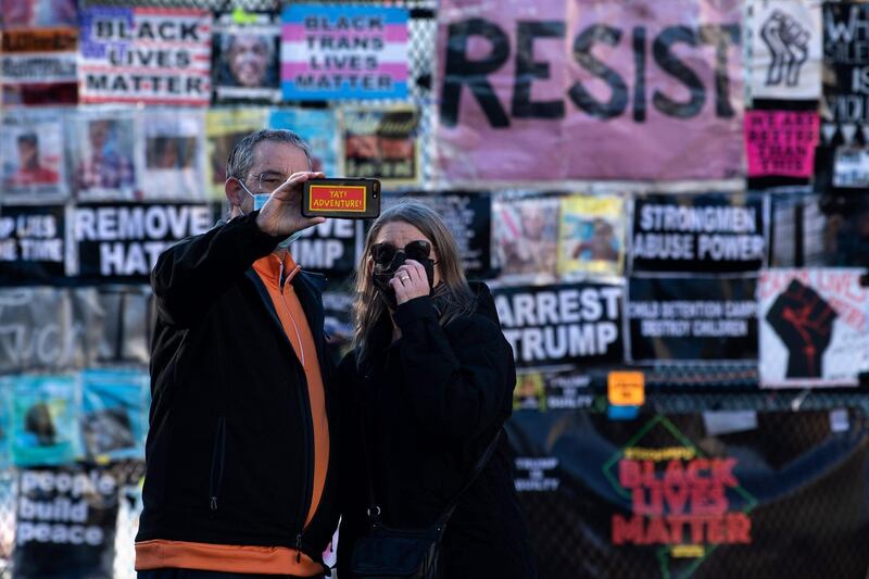 People take a selfie at a temporary security fence around the White House  covered in protest posters, as the 2020 US presidential election remains undecided, in Washington, DC. President Donald Trump and Democratic challenger Joe Biden are battling it out for the White House, with polls closed across the United States -- and the American people waiting for results in key battlegrounds still up for grabs. AFP