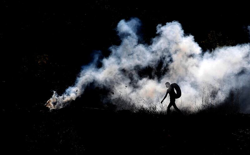 A Palestinian walks through tear gas during violence near the West Bank city of Nablus. EPA