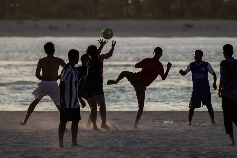 Friends play beach football at the Corniche during sunset. Victor Besa / The National