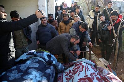 Mourners stand next to bodies of people killed in an air strike in Idlib, Syria, on December 26.  EPA