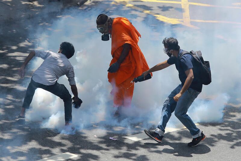 Demonstrators react after police fired tear gas to disperse their protest in Colombo, Sri Lanka. Protesters demanding that President Gotabaya Rajapaksa resign forced their way into his official residence on Saturday, a local television report said, as thousands of people took to the streets in the capital decrying the island nation's worst economic crisis in recent memory. AP 