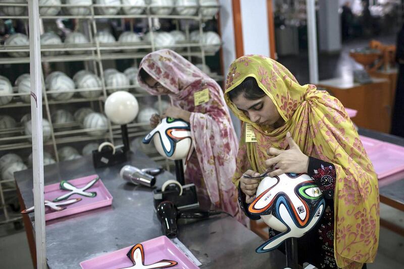 An employee adjusts outer panels on a football inside the factory. Sara Farid / Reuters


