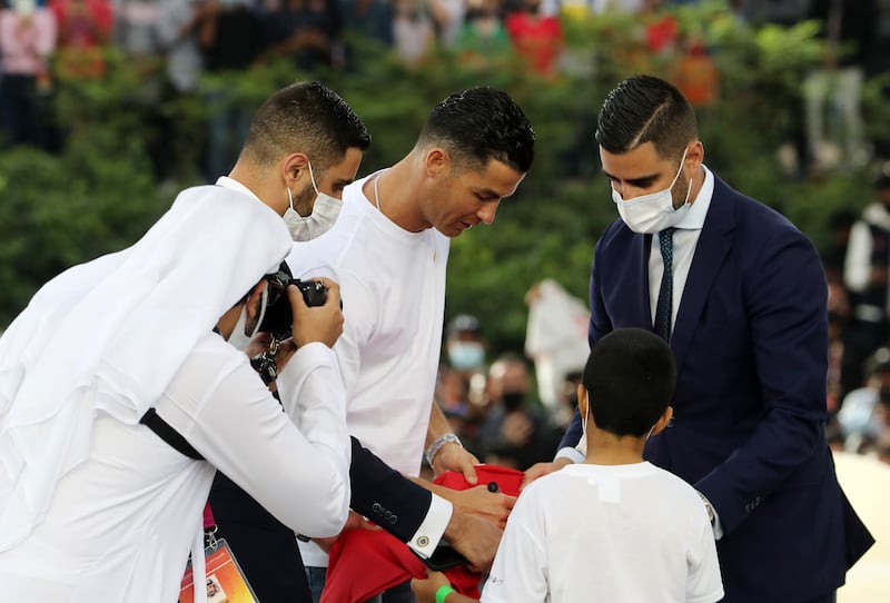 The five-times Champions League winner signs a shirt to present to a young fan.
