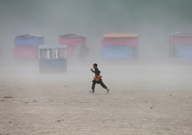 A boy runs during a dust storm at the Qargha Lake. Reuters