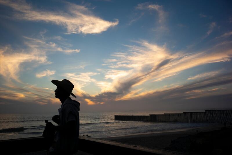 A man looks out near where the border wall, right, separating San Diego from Tijuana, Mexico. AP Photo