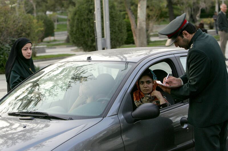 An Iranian police officer stops a car during a crackdown to enforce the dress code for women. AFP