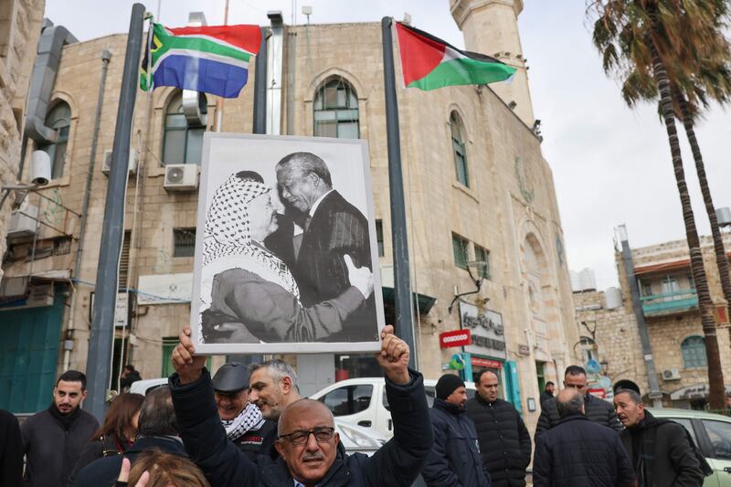 A Palestinian man holds a portrait of late PLO leader Yasser Arafat and former South African president Nelson Mandela in Bethlehem last week. AFP